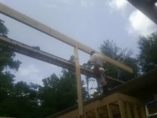 Carpenter setting a ridge beam over a new addition frame — Ice Dam Removal by Roofing Brothers in Mamou