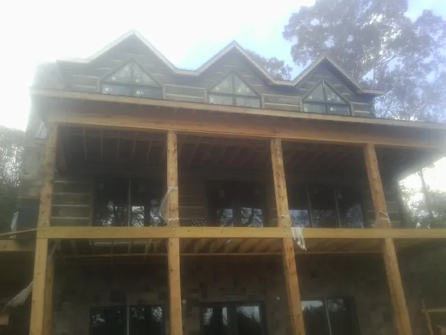 Dormers and porch framing on a large log home under construction — Roof Coating work by our crew in Mamou