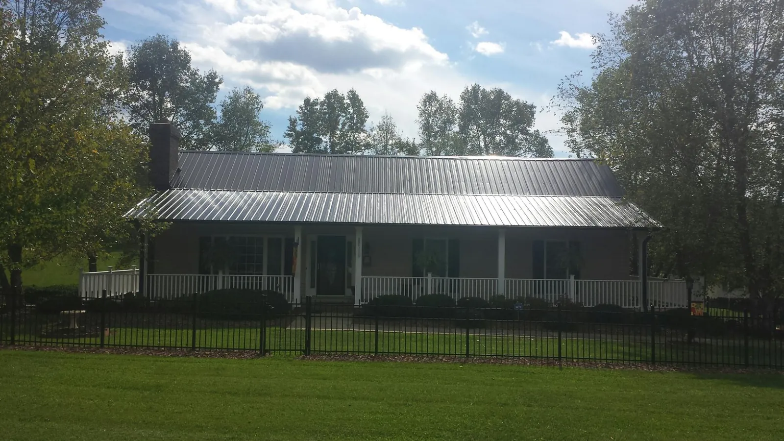 Gray metal roof on a brick ranch with a full width front porch — Gutter Guard Installation work by our crew in Mamou