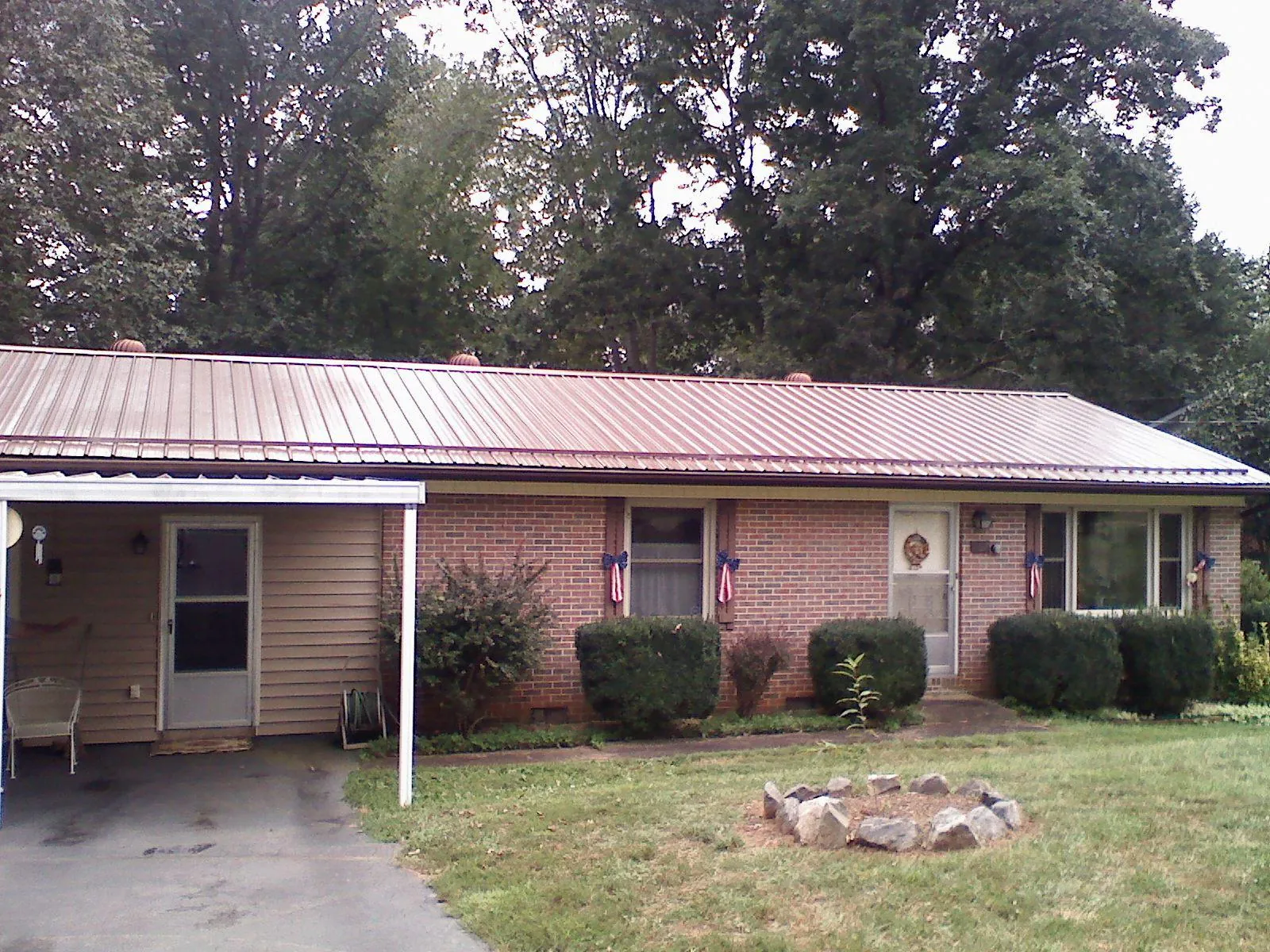 Bronze metal roof and carport on a brick ranch home — Roof Repair work by our crew in Mamou