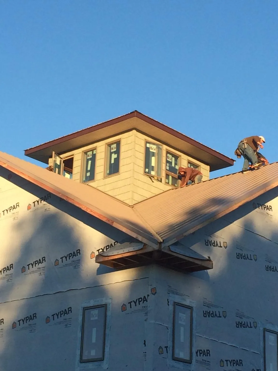 Roofers working around a rooftop cupola on a new metal roof at sunset — Roof Waterproofing in Mamou by Roofing Brothers